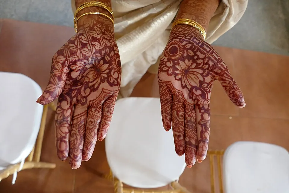 A hand decorated with intricate henna mehndi patterns, showing floral and geometric designs in reddish-brown dye, demonstrating the South Asian and Middle Eastern tradition of temporary body painting for weddings and festivals