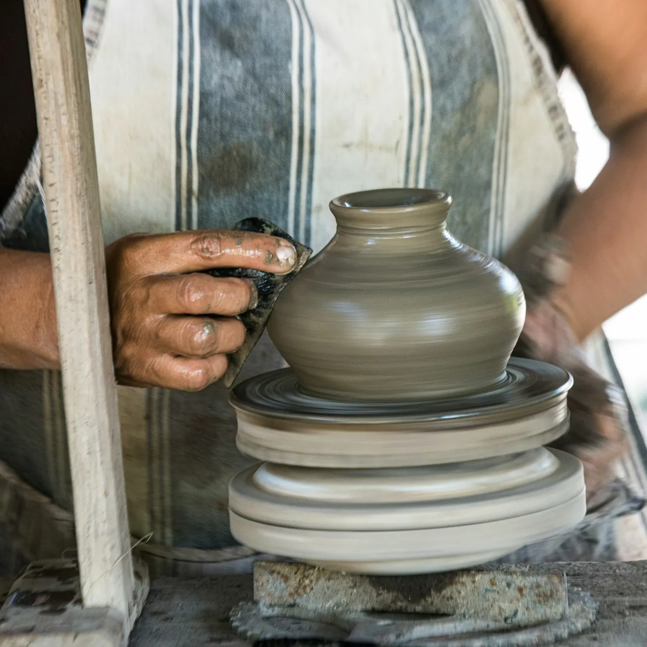Hands holding a finished ceramic bowl, showing the natural variation in texture and glaze typical of studio pottery