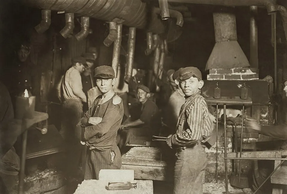 Midnight at the Glassworks (1908) by Lewis Hine, showing young boys working at night in a glass factory, their faces lit by furnace light