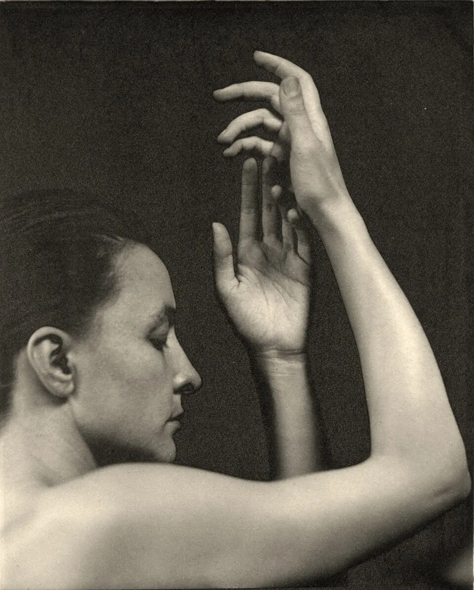 Black and white photograph of Georgia O'Keeffe by Alfred Stieglitz showing her hands raised near her face
