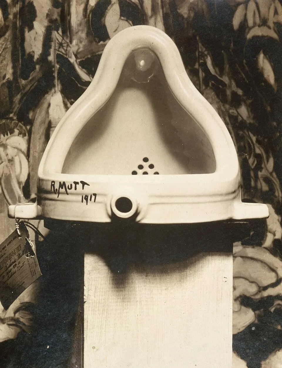 Marcel Duchamp's Fountain (1917), a porcelain urinal signed R. Mutt and photographed by Alfred Stieglitz against a backdrop of Marsden Hartley's painting, demonstrating how gallery context transforms an everyday object into art
