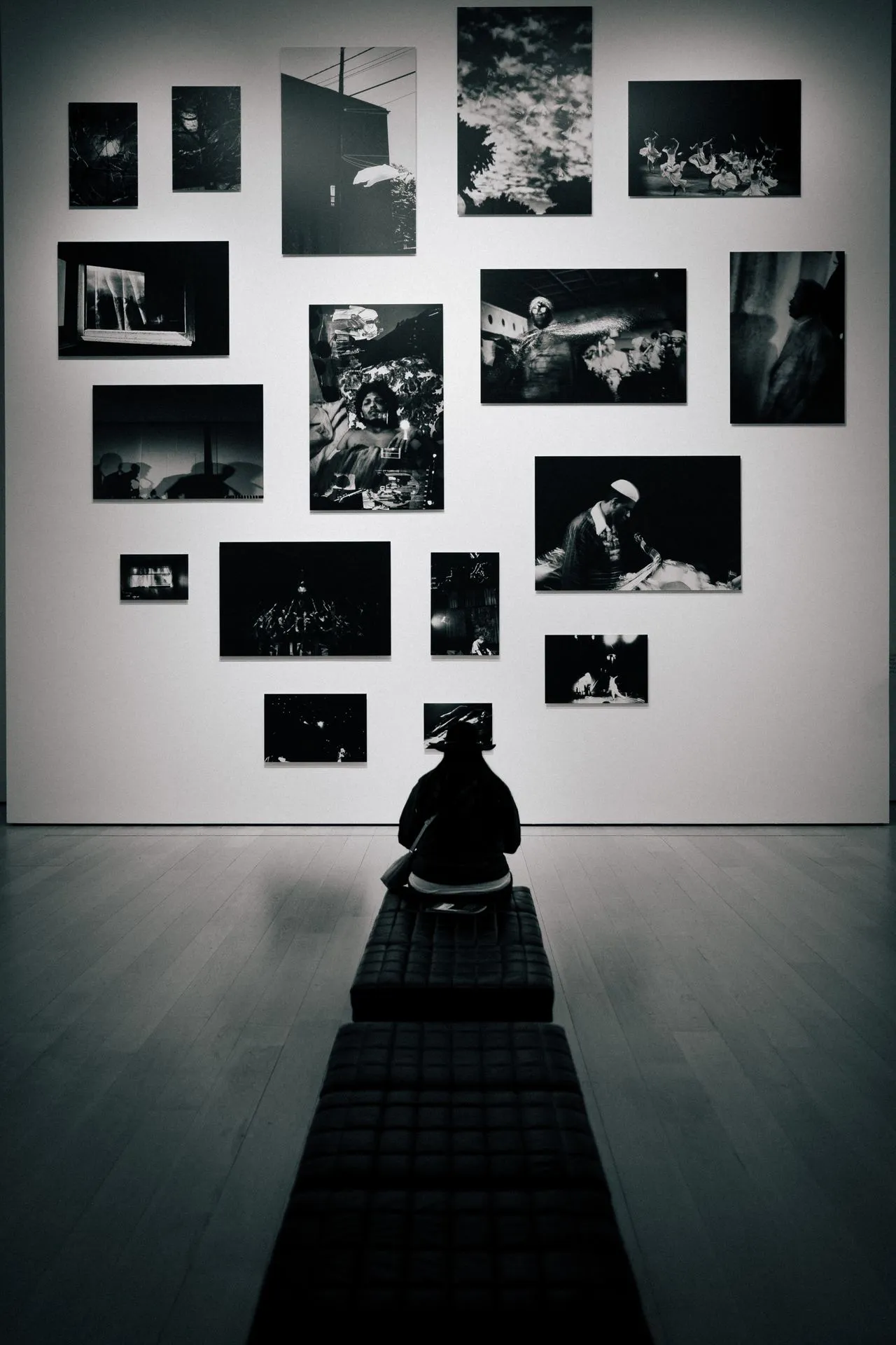 A person sitting on a gallery bench, focused intensely on a single artwork