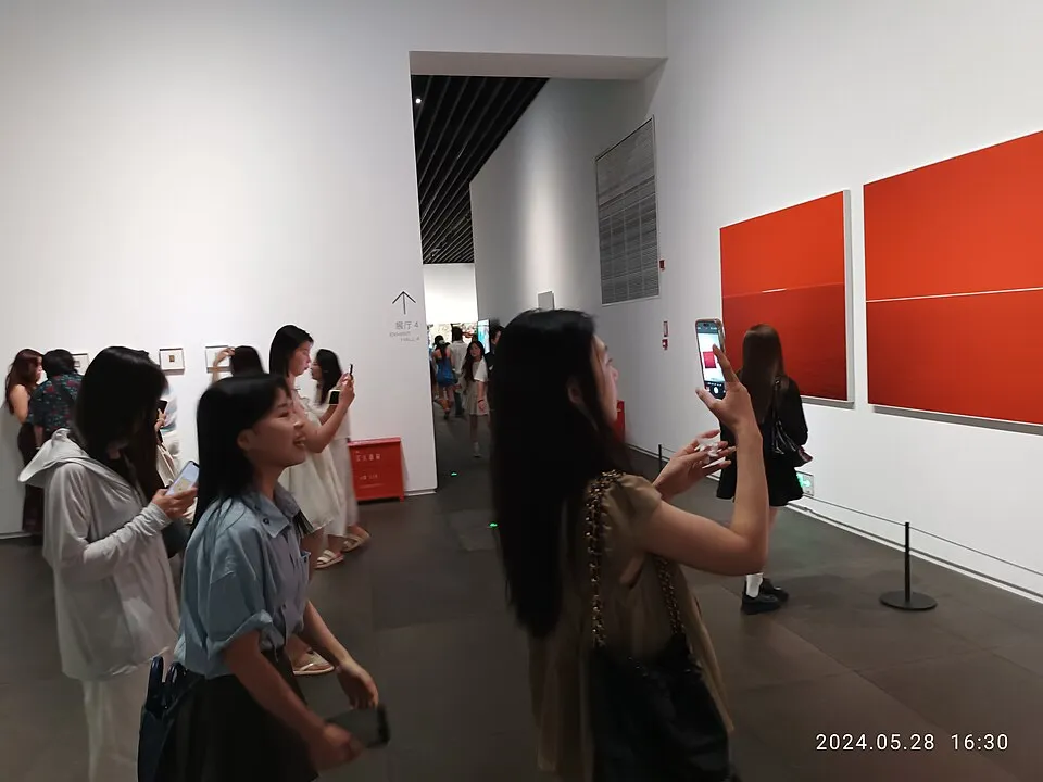 A visitor in a museum gallery using a smartphone, the modern museum experience where apps and audio guides have replaced the clunky rented devices of the past, allowing visitors to explore at their own pace with rich contextual information