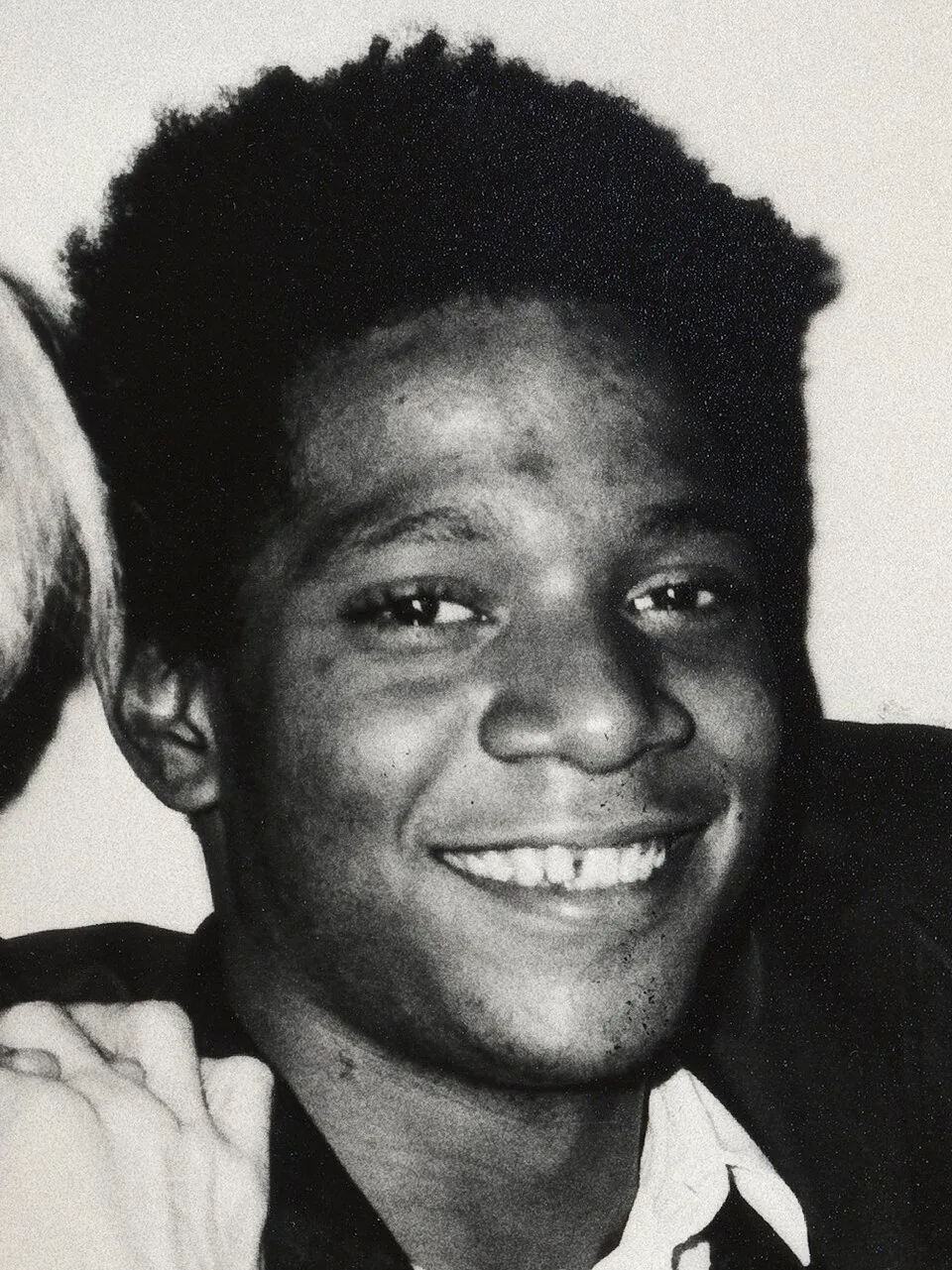 Black and white photograph of Jean-Michel Basquiat painting in his studio