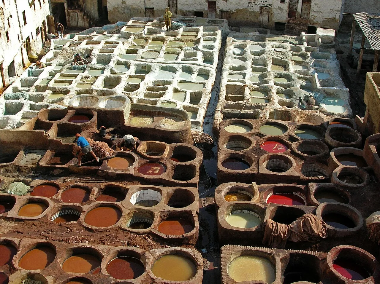 The tanneries of Fez, Morocco, showing the circular stone dyeing vats filled with coloured dye in which leather hides are soaked, with workers processing hides in the traditional way