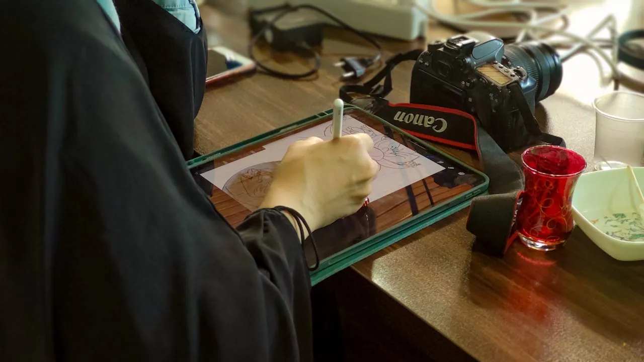 Person drawing on a digital tablet with a stylus at a desk.
