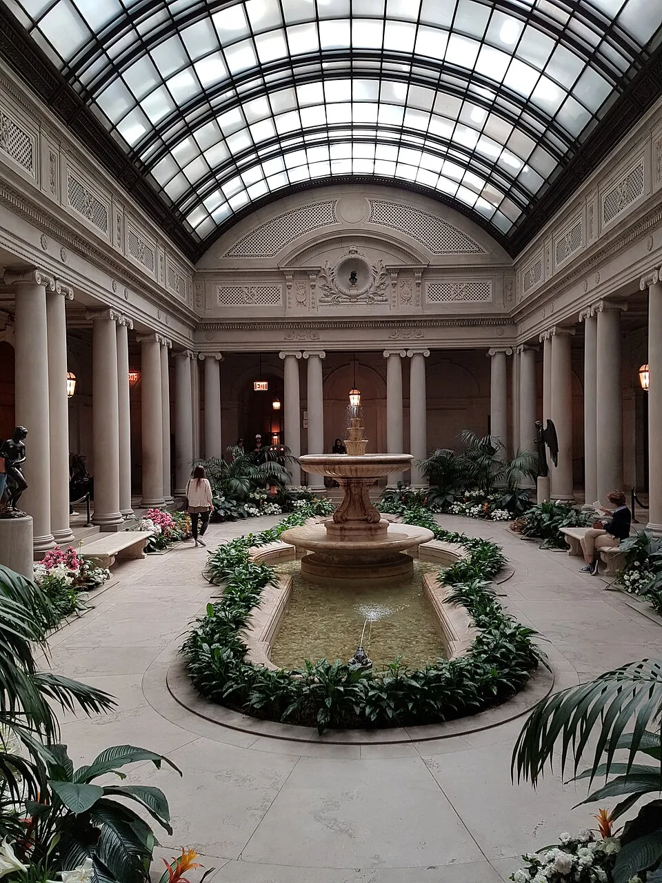 The Frick Collection interior, showing a furnished gallery room with paintings hung salon-style above antique furniture and a fireplace