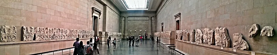 The Parthenon Marbles in the Duveen Gallery at the British Museum, showing marble frieze panels and pediment figures displayed at eye level along the gallery walls.