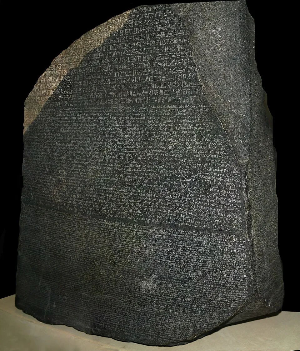 The Rosetta Stone, a dark granodiorite stele with inscriptions in three scripts: hieroglyphs, demotic, and ancient Greek, displayed at the British Museum.