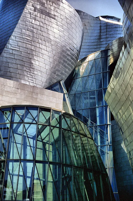 Detail of the Guggenheim Bilbao's facade, showing the curved reflective titanium surface catching sunlight.