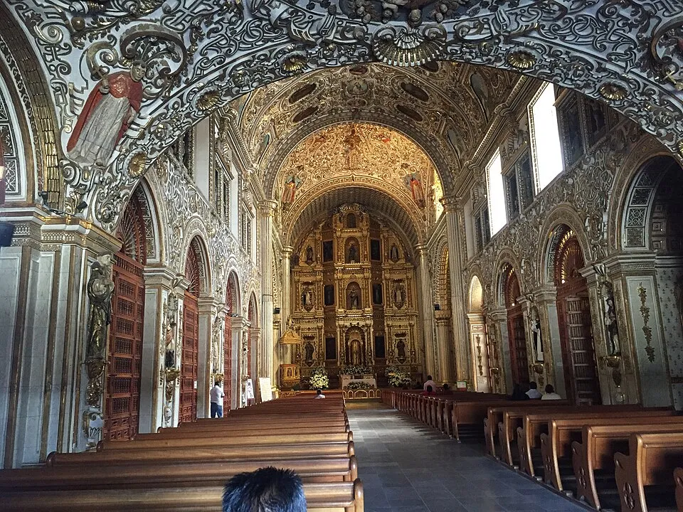 Interior of the Church of Santo Domingo de Guzmán in Oaxaca, Mexico, showing ornate Baroque decoration with rich red tones derived from cochineal dye