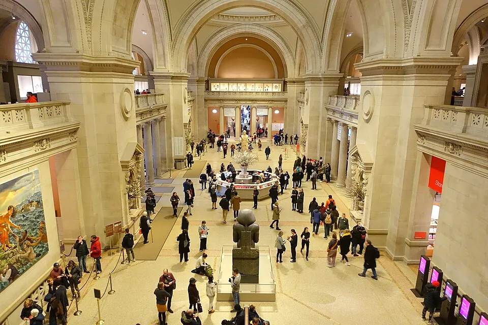 The Great Hall of the Metropolitan Museum of Art, a vast vaulted entrance hall with floral arrangements and information desks.