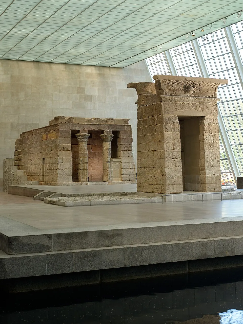 The Temple of Dendur in the Sackler Wing at the Metropolitan Museum of Art. An ancient Egyptian temple reconstructed inside a glass-walled room with a reflecting pool.