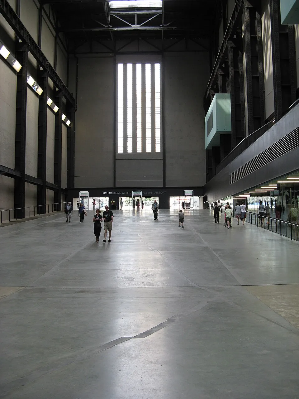 The Turbine Hall at Tate Modern, a vast industrial space with a ramp descending into it, concrete floors and brick walls from the former power station.