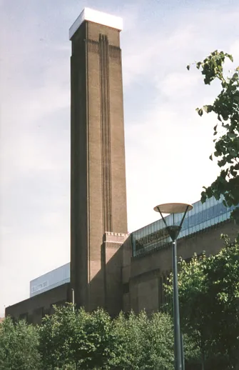 Tate Modern building exterior, the former Bankside Power Station with its iconic brick facade and central chimney on the south bank of the Thames.