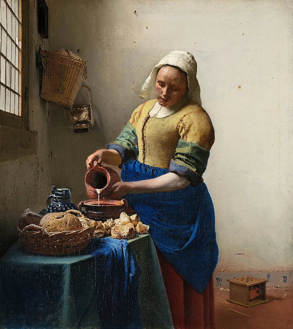 The Milkmaid (c. 1658) by Johannes Vermeer, showing a woman pouring milk from a jug in a sunlit kitchen, positioned along the left third of the canvas