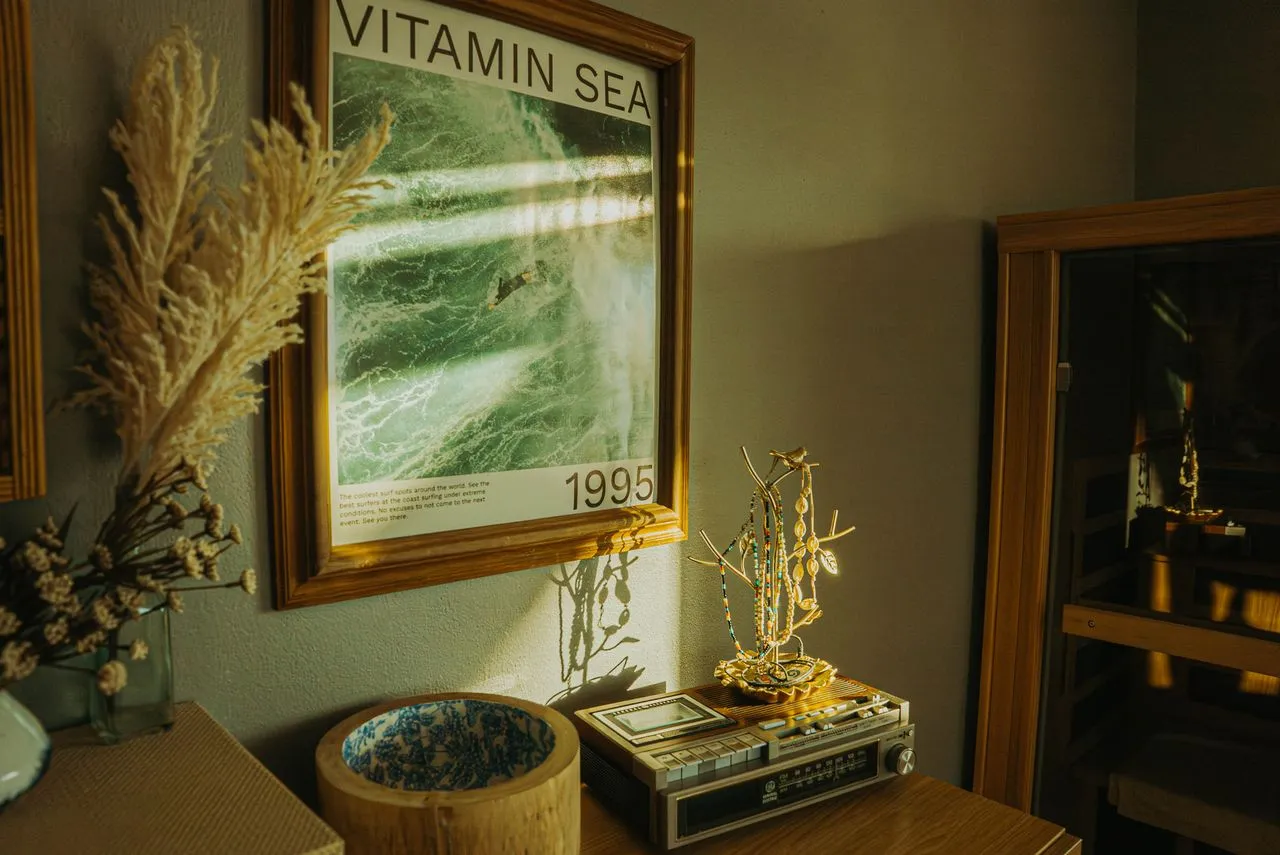 A styled living room with framed wall art pieces arranged above a sofa, showing a mix of sizes and frame styles