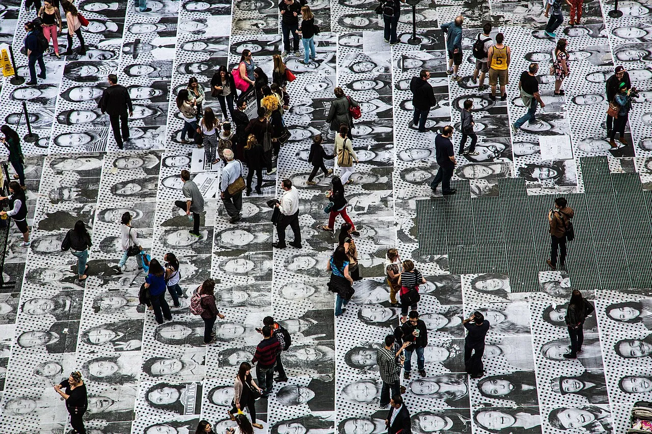 JR Inside Out project pasteup in Times Square, New York, showing a large-scale portrait pasted on a building facade as part of the artist's global participatory street art project