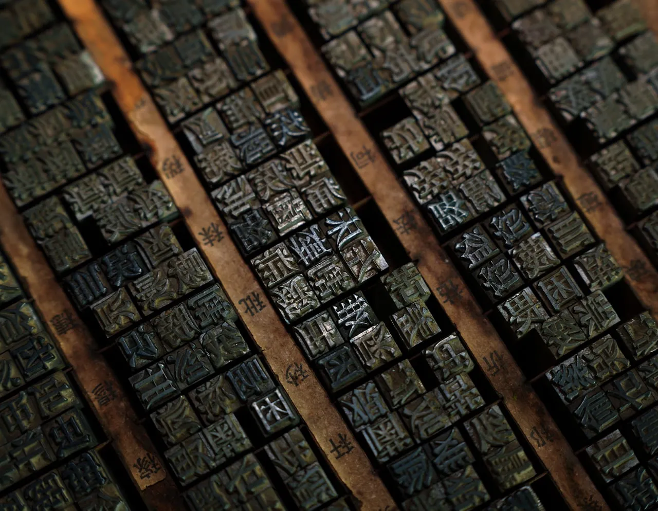 Close-up of antique wooden letterpress type blocks, showing the relief surface and worn character of hand-carved or cast printing blocks