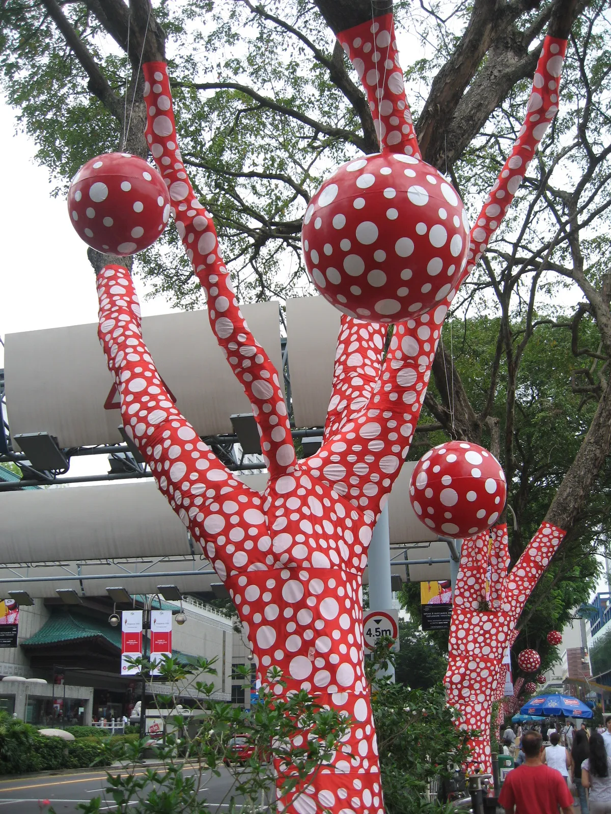 Trees wrapped in red polka-dotted fabric as part of Yayoi Kusama's Ascension of Polka Dots on the Trees installation at the Singapore Biennale 2006
