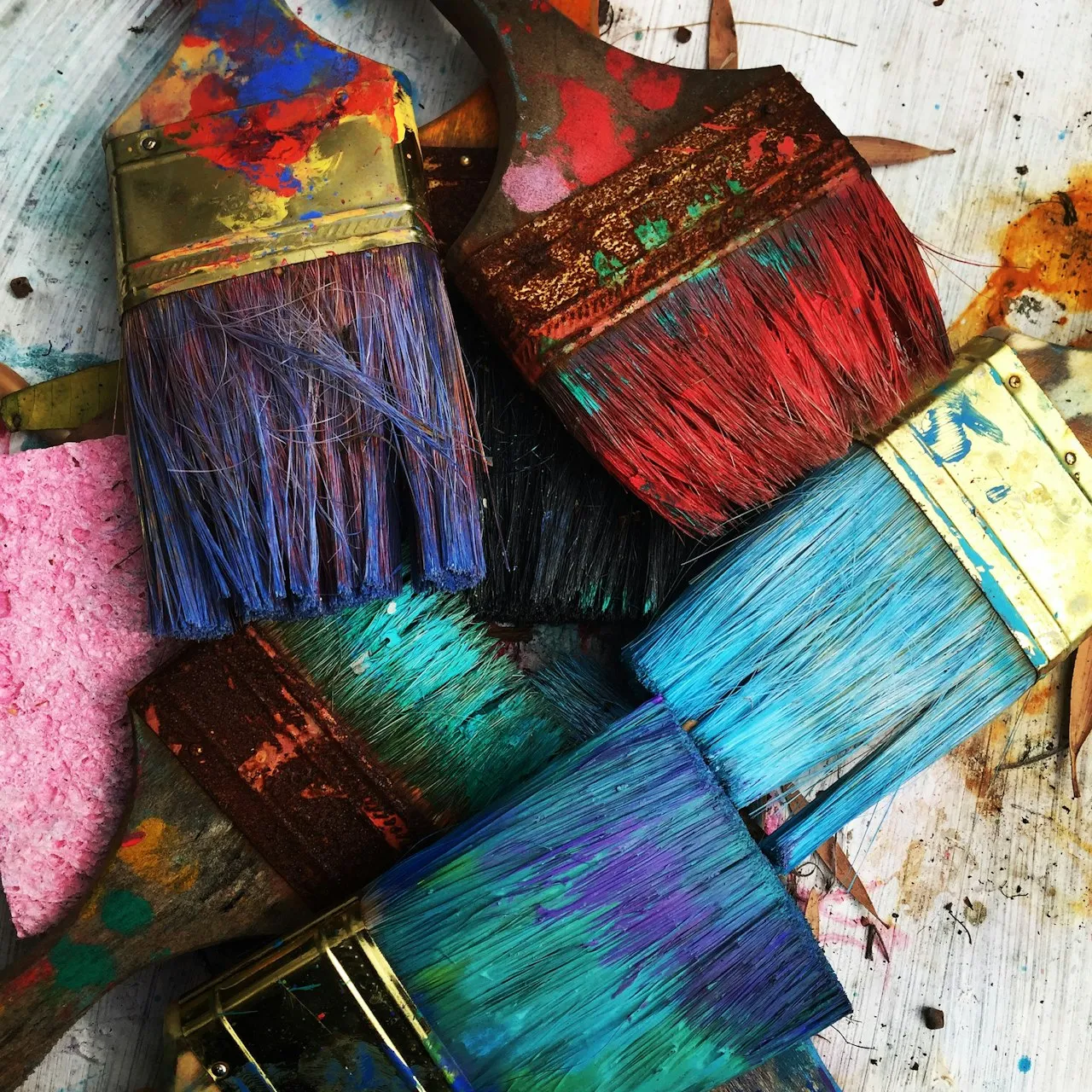 A person's hands working with colorful paints on a canvas, demonstrating the therapeutic process of art-making